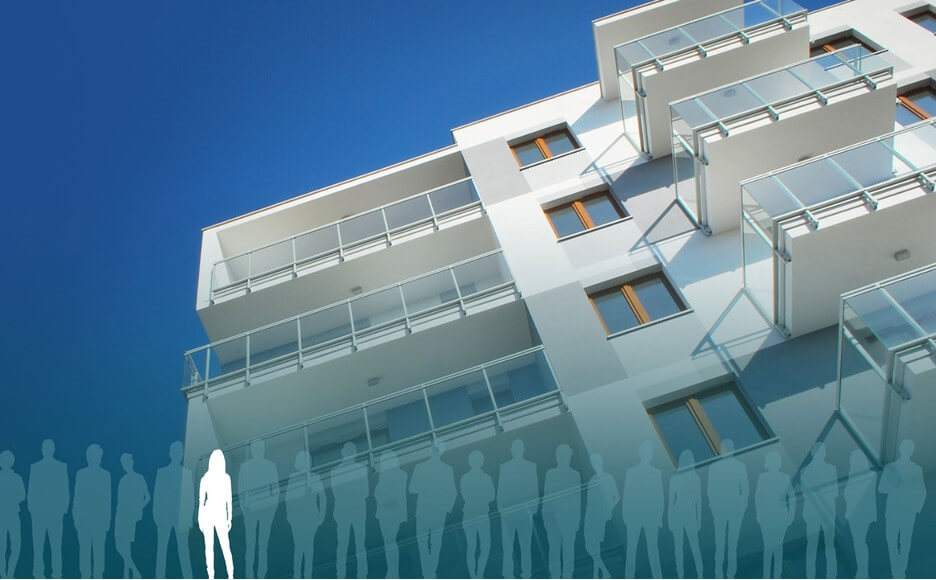 Modern apartment building facade with balconies, against a clear blue sky, silhouettes of people at the bottom.