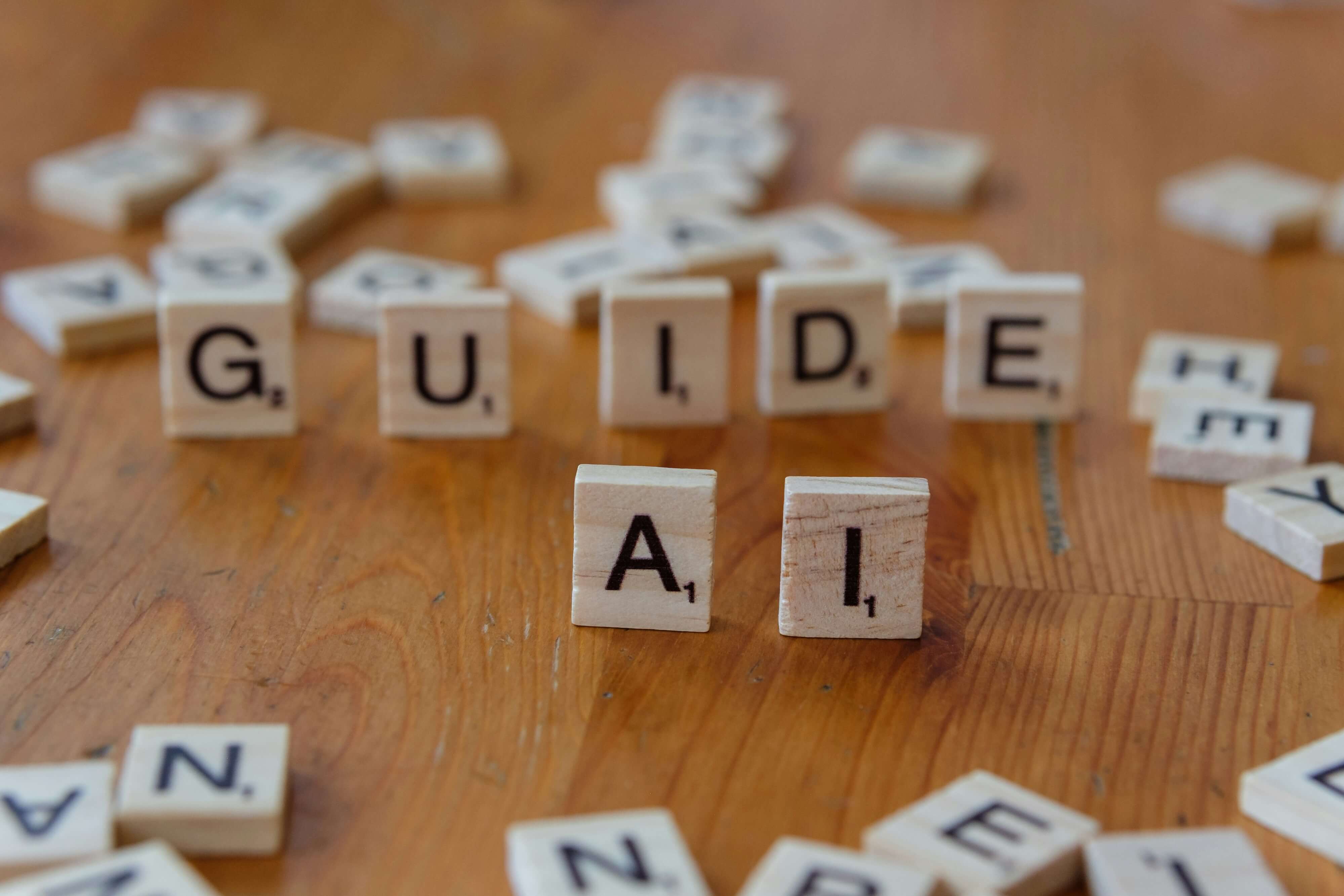 Scrabble tiles arranged to spell 'GUIDE AI' on a wooden surface, with scattered tiles in the background.
