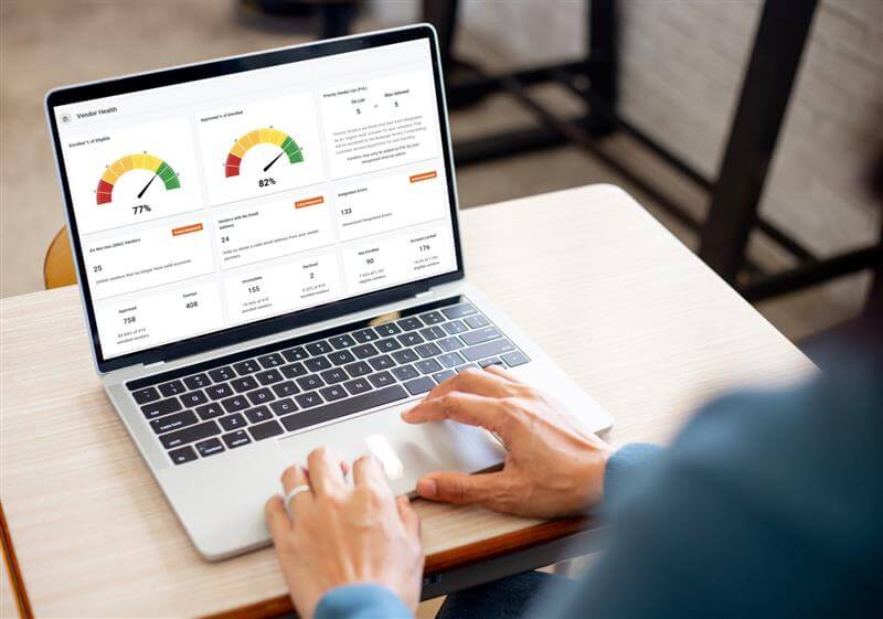 A person using a laptop displaying vendor health metrics with gauges and statistics.